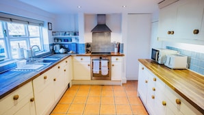 A modern kitchen with white cabinets, a stainless steel oven, and a wooden countertop. - The Leam Terrace Escape 3 Bed Townhouse (Royal Leamington Spa)