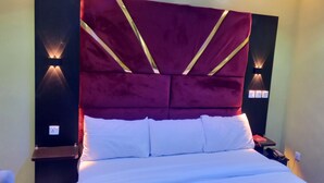 Ein Bett mit einem roten, gepolsterten Kopfteil und weißer Bettwäsche.