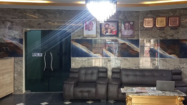 Eine Empfangshalle mit Glastür, einer Couch, einem Couchtisch und gerahmten Bildern an der Wand.