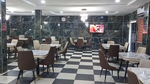 Ein Restaurant mit Marmorwänden, kariertem Boden und mehreren Tischen und Stühlen.