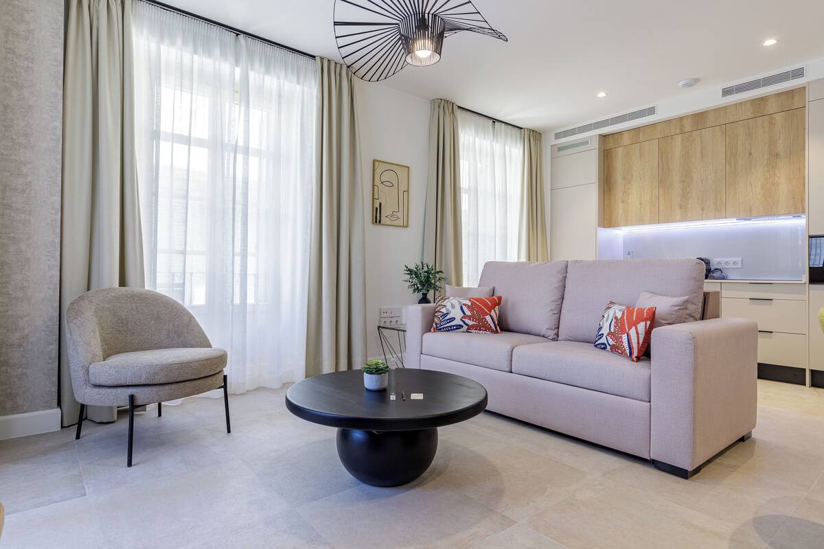 Un salon moderne avec un canapé, un fauteuil et une table basse ronde.