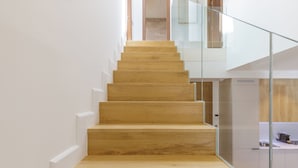 A modern staircase with wooden steps and glass railings leading to a second floor. - Plaza del Siglo Suites (Málaga)