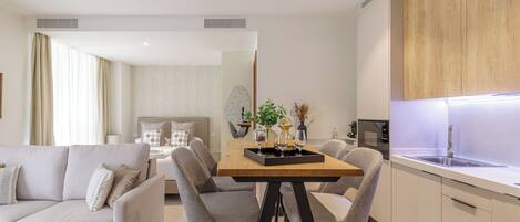 Una cocina moderna con encimera de madera, horno empotrado y lavamanos. Hay un comedor con mesa y sillas de madera.