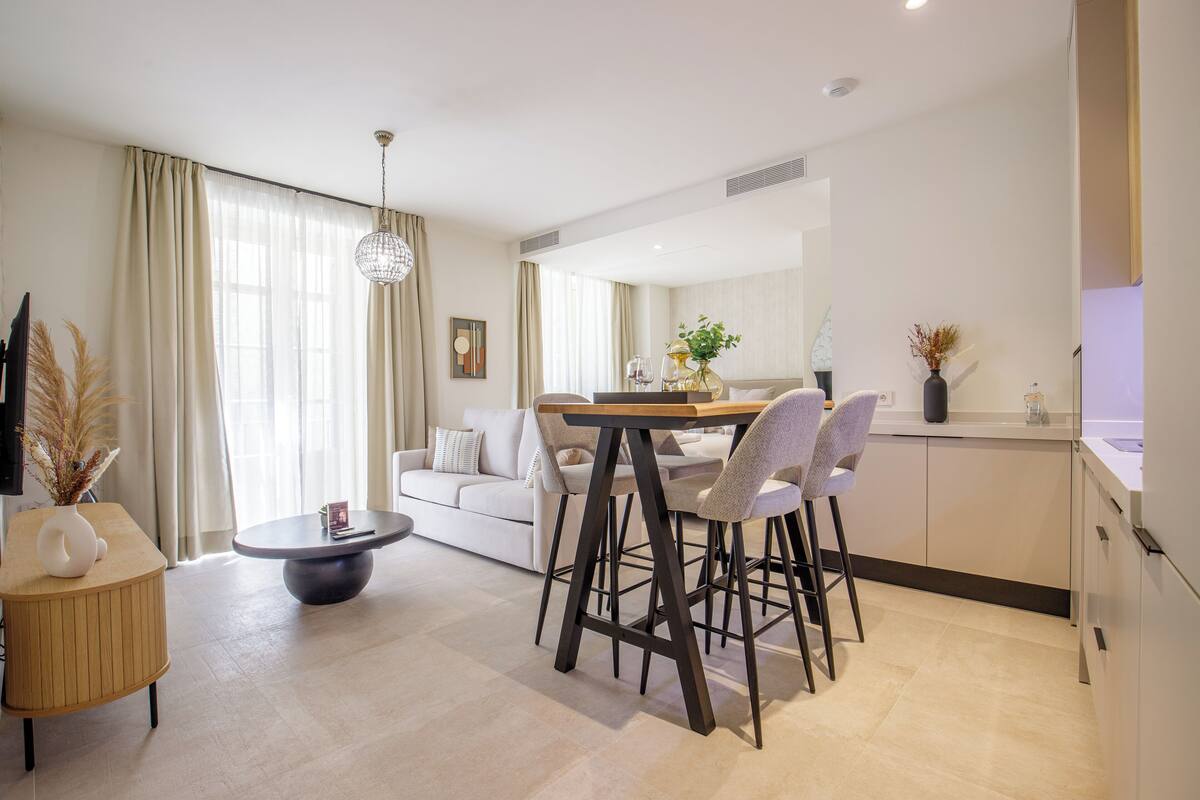 Un salon moderne avec un coin repas, un canapé, une table basse et une cuisine en arrière-plan.