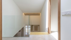 A modern interior with a glass staircase, minimalist design, and a view to another room. - Plaza del Siglo Suites (Málaga)
