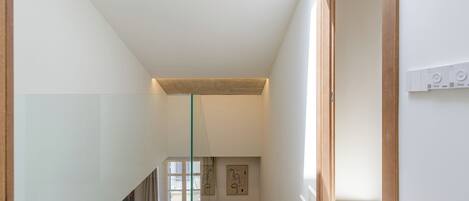 A modern interior with a glass staircase, minimalist design, and a view to another room.