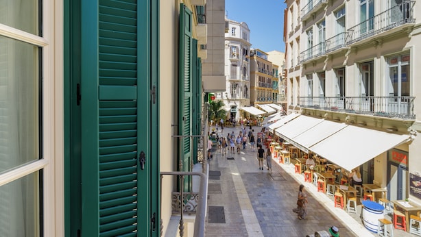 A narrow street with buildings on either side, outdoor seating areas, and a clear sky. - Plaza del Siglo Suites (Málaga)