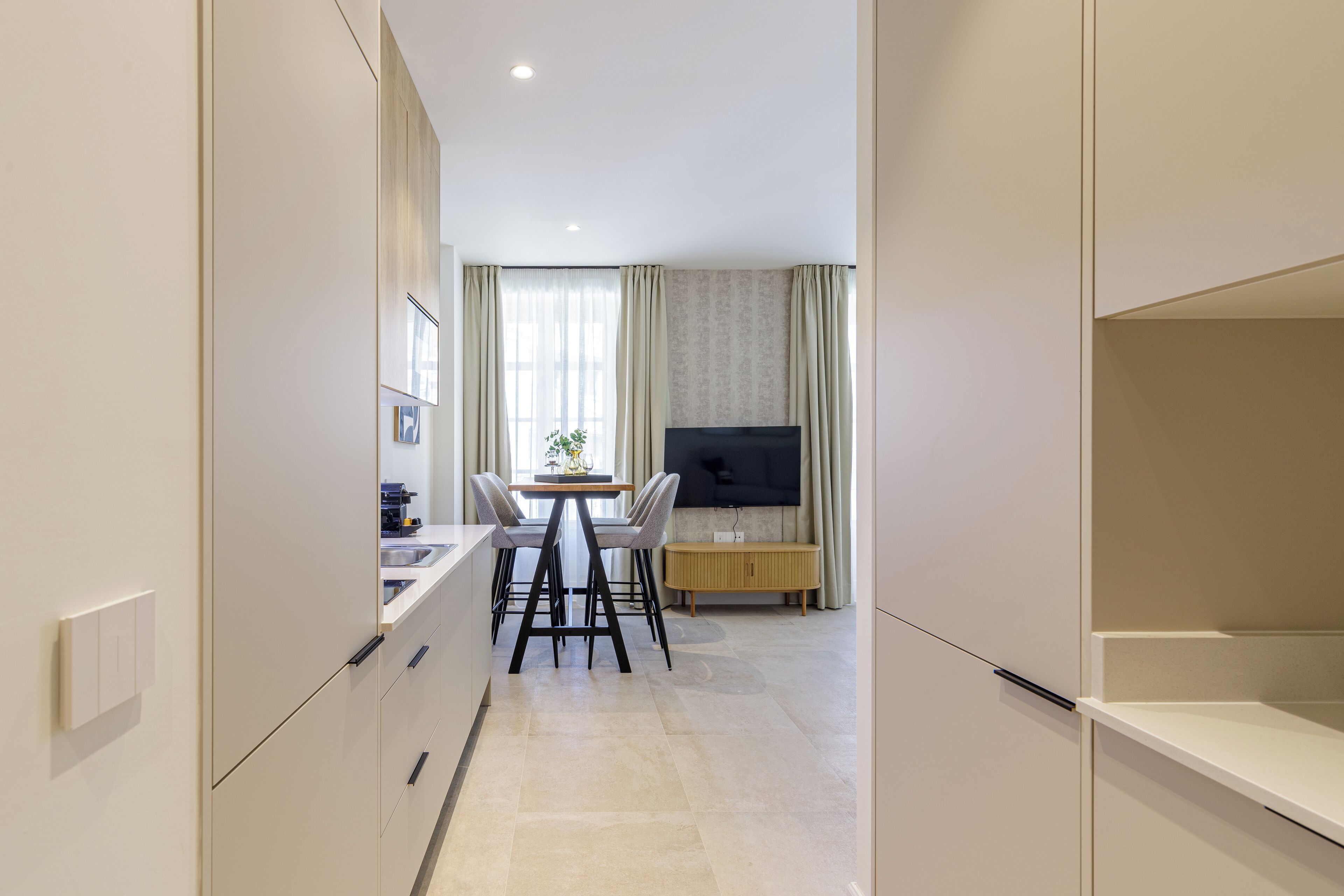 Una cocina moderna con zona de comedor, televisor de pantalla plana y ventana con cortinas.