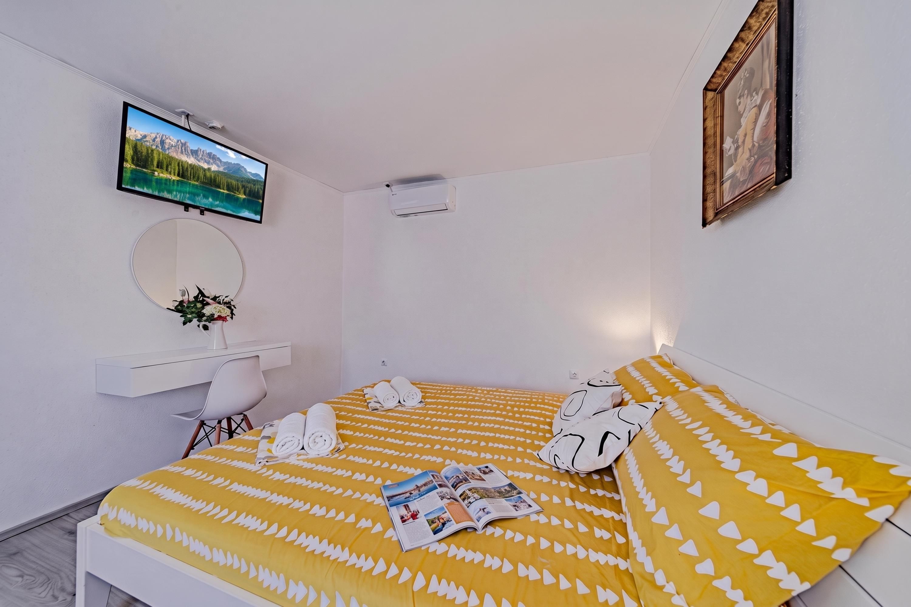 Une chambre d’hôtel comprenant un lit, un bureau, une chaise, un miroir, un téléviseur et un tableau encadré accroché au mur.