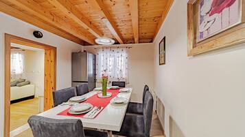 A dining area with a wooden ceiling, a dining table set with plates, and a vase of flowers.