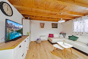 A modern living room with a wooden ceiling, a flat-screen TV, a sofa, a coffee table, and a wall-mounted clock. - Holiday Home Luce with Pool (Seget)