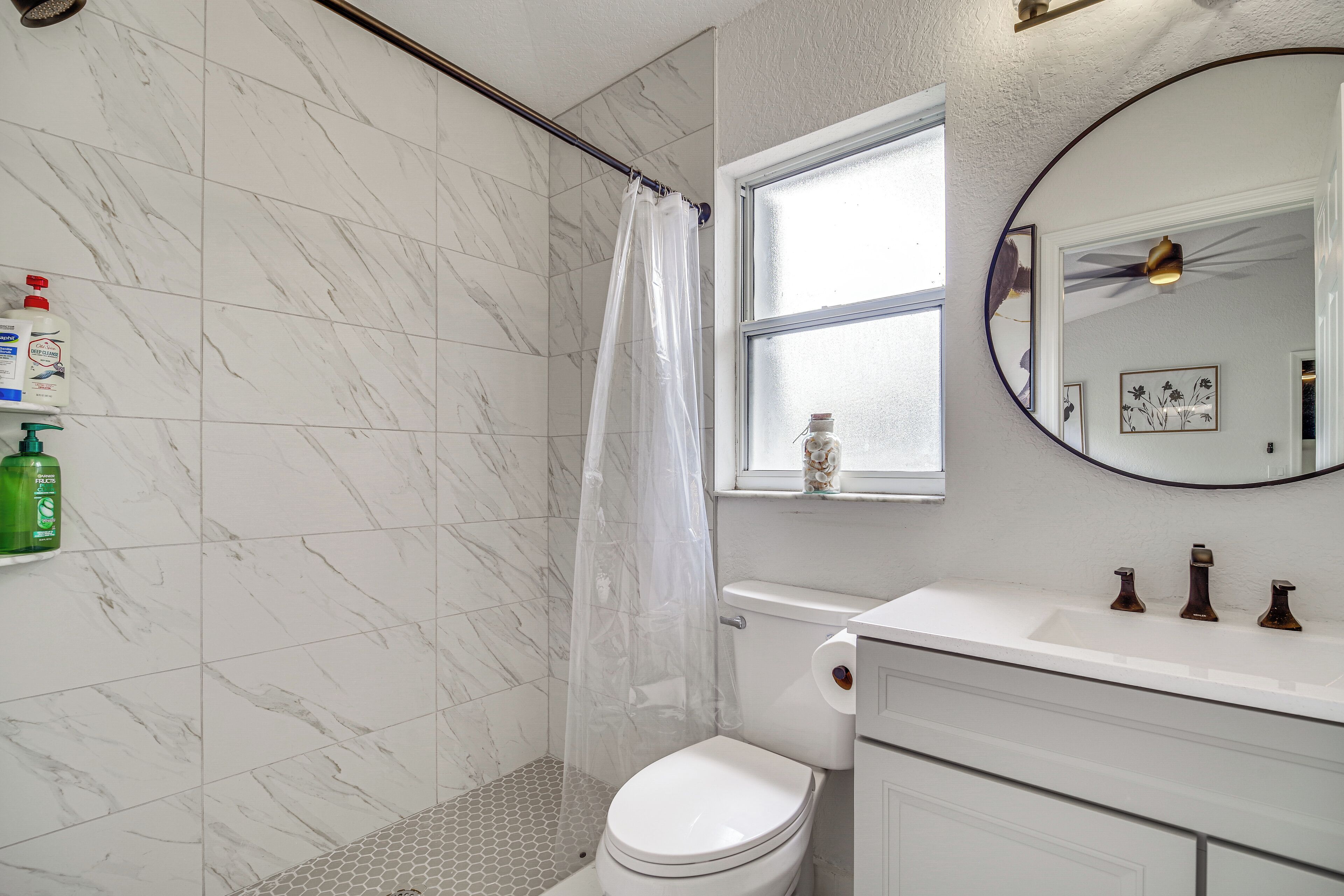 Une salle de bain avec douche, toilettes et lavabo.