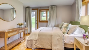 A bedroom with a bed, bedside table, mirror, and a window with curtains.