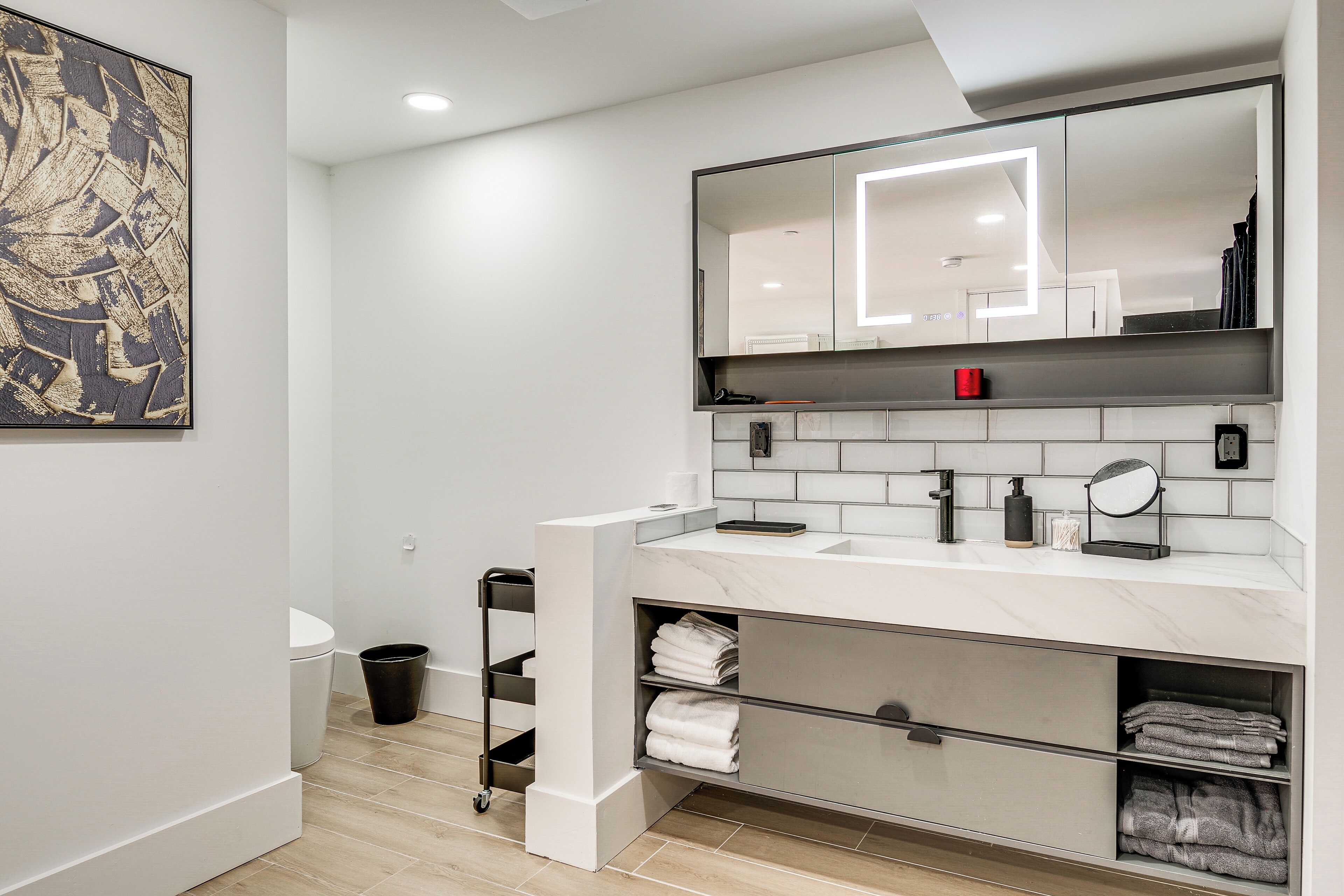 A modern bathroom with a white vanity, a large mirror, and a towel rack.