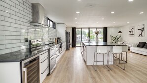 A modern kitchen with a central island, stainless steel appliances, and a view to the outdoors. - Lakefront Lynnwood Home w/ Balconies & Shared Dock (Lynnwood)