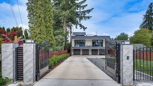 A modern two-story house with a gated driveway, surrounded by trees and a well-maintained garden. - Lakefront Lynnwood Home w/ Balconies & Shared Dock (Lynnwood)