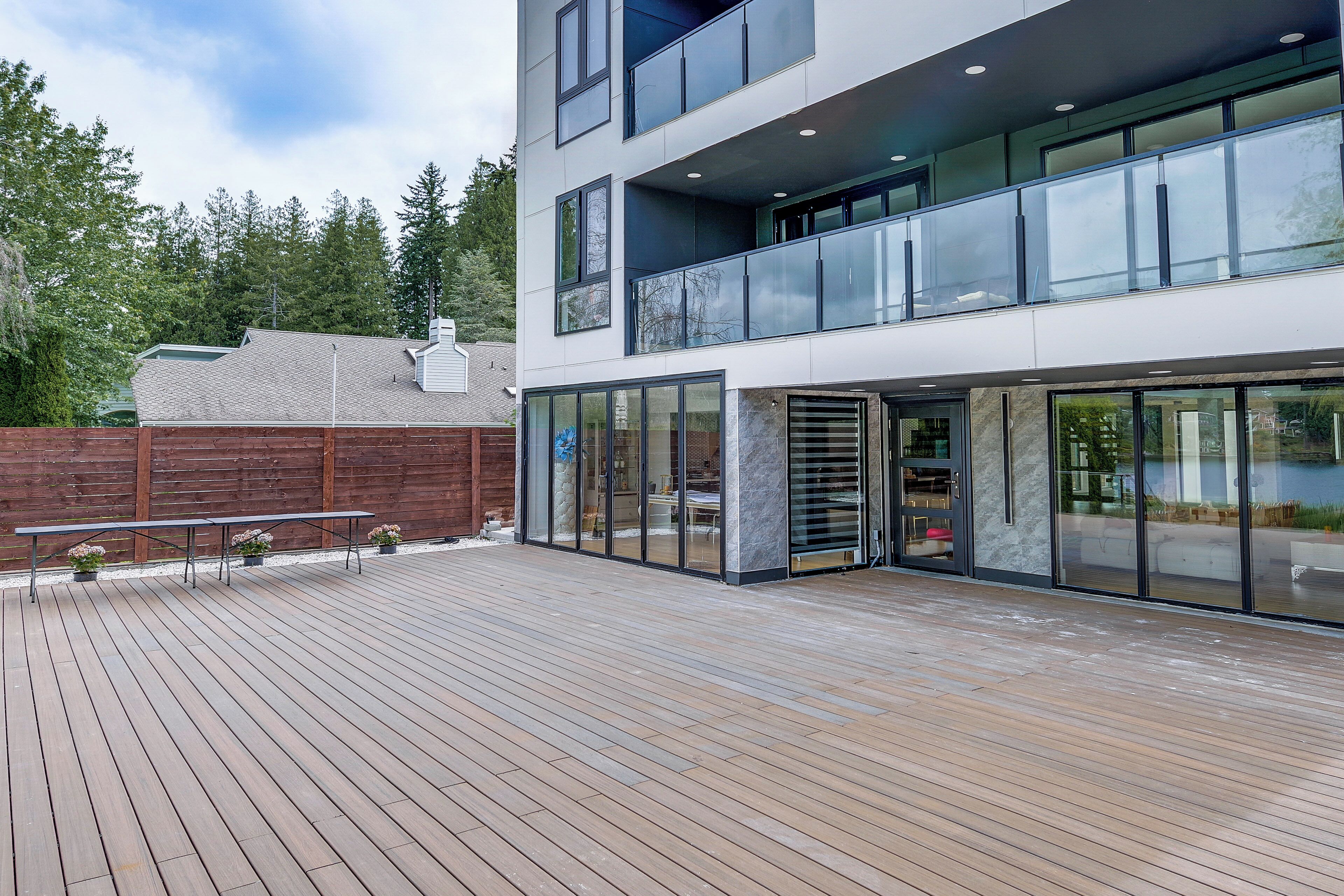 A modern building with a wooden deck, large windows, and a balcony.