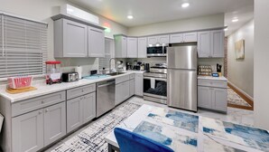 A modern kitchen with grey cabinets, stainless steel appliances, and a white countertop. - Hot Springs Home w/ Yard, Walk to Bathhouse Row! (Hot Springs)