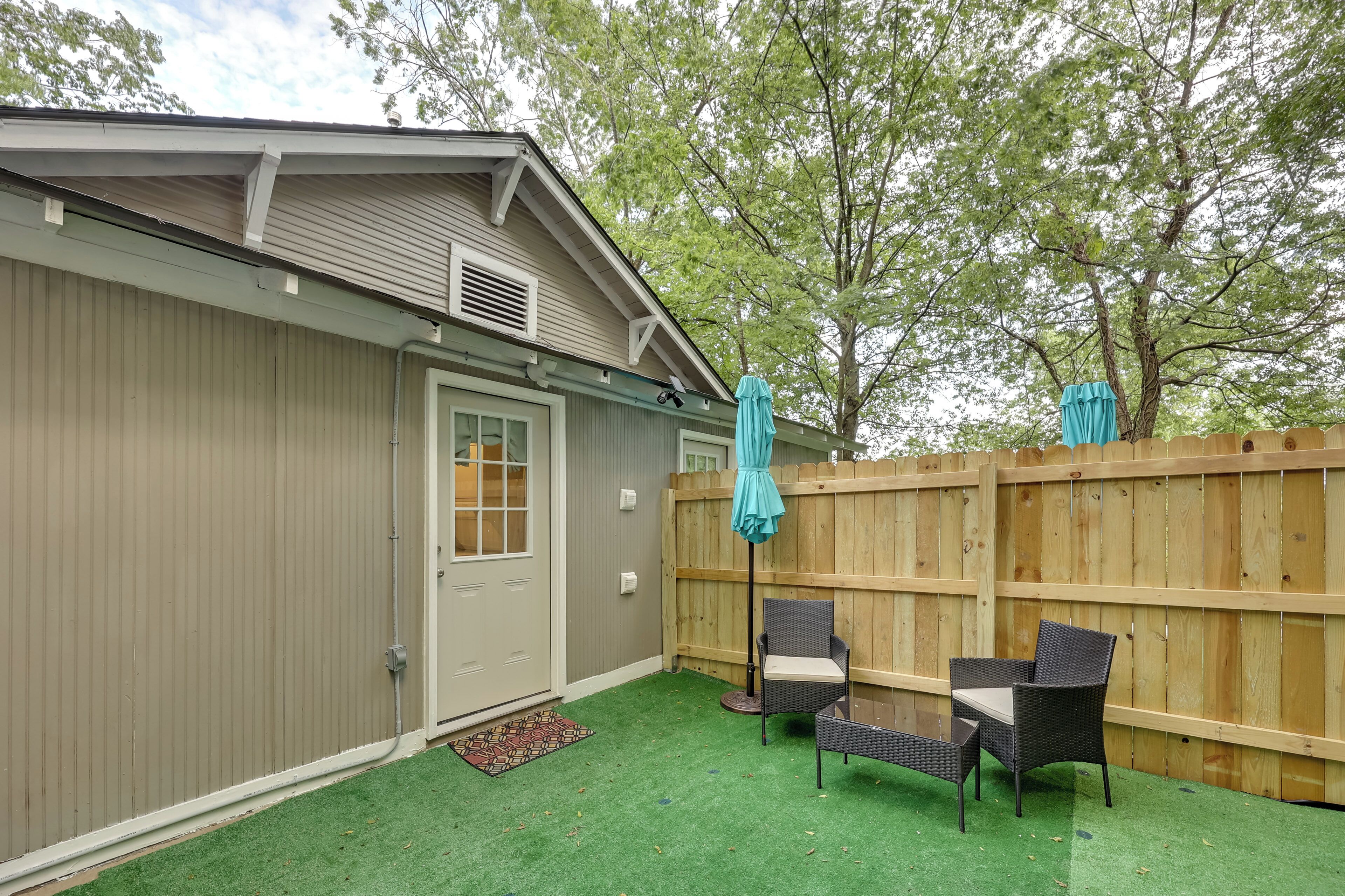 A backyard with a wooden fence, a door, and two wicker chairs.