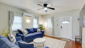 A living room with a blue sofa set, a white coffee table, and a ceiling fan. - Hot Springs Home w/ Yard, Walk to Bathhouse Row! (Hot Springs)