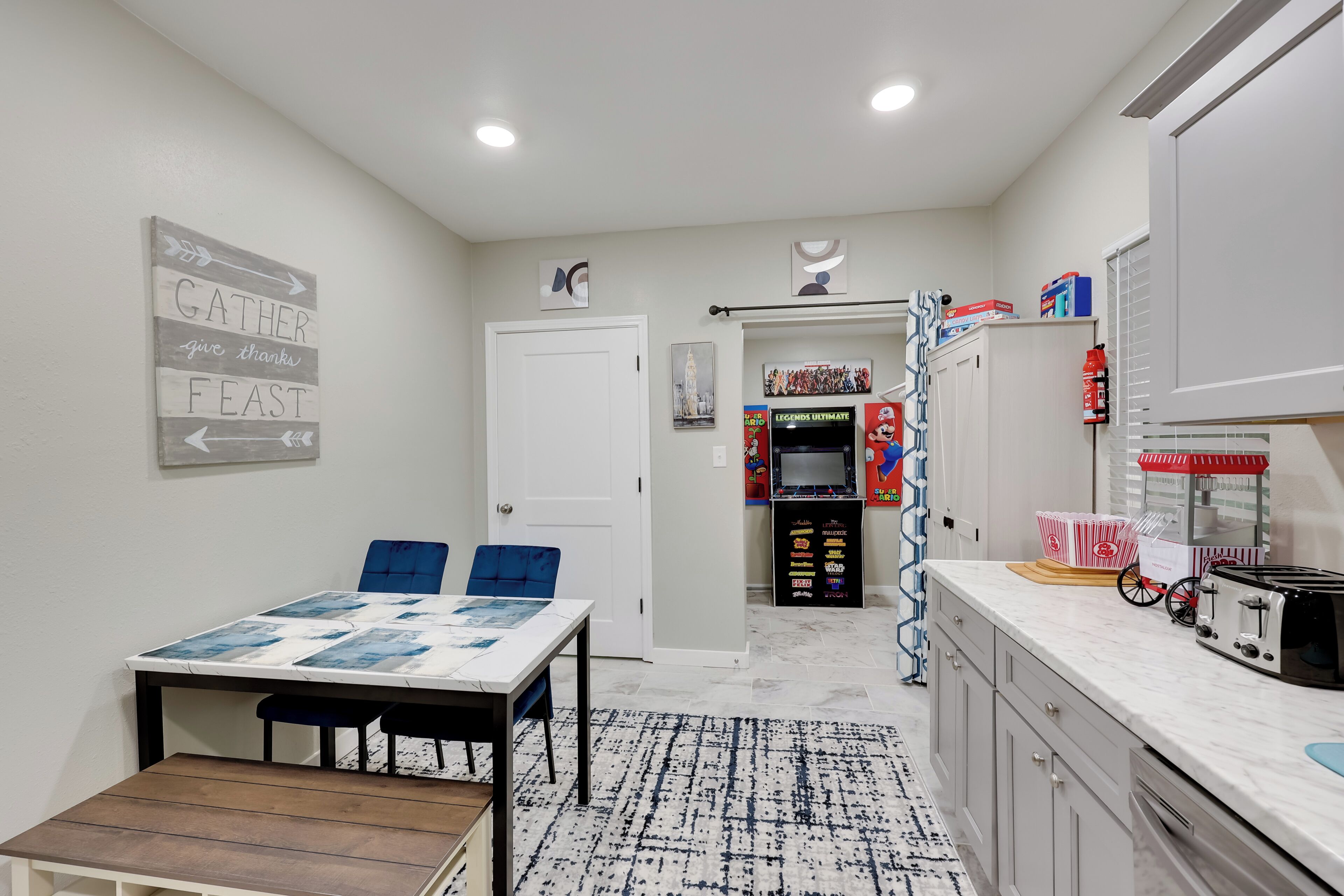 A compact kitchen with a dining area, featuring a table with chairs, a microwave, and a small refrigerator.