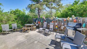 An outdoor patio with metal chairs, a wooden table, and a barbecue grill.