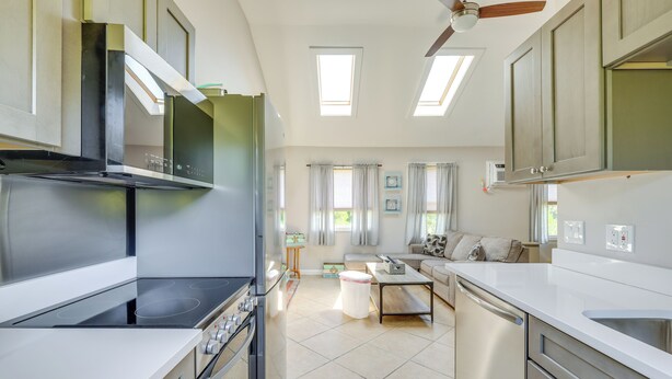 A modern kitchen with a built-in stove, oven, and dishwasher. There is a dining area with a table and chairs, and a living room with a sofa and a coffee table.