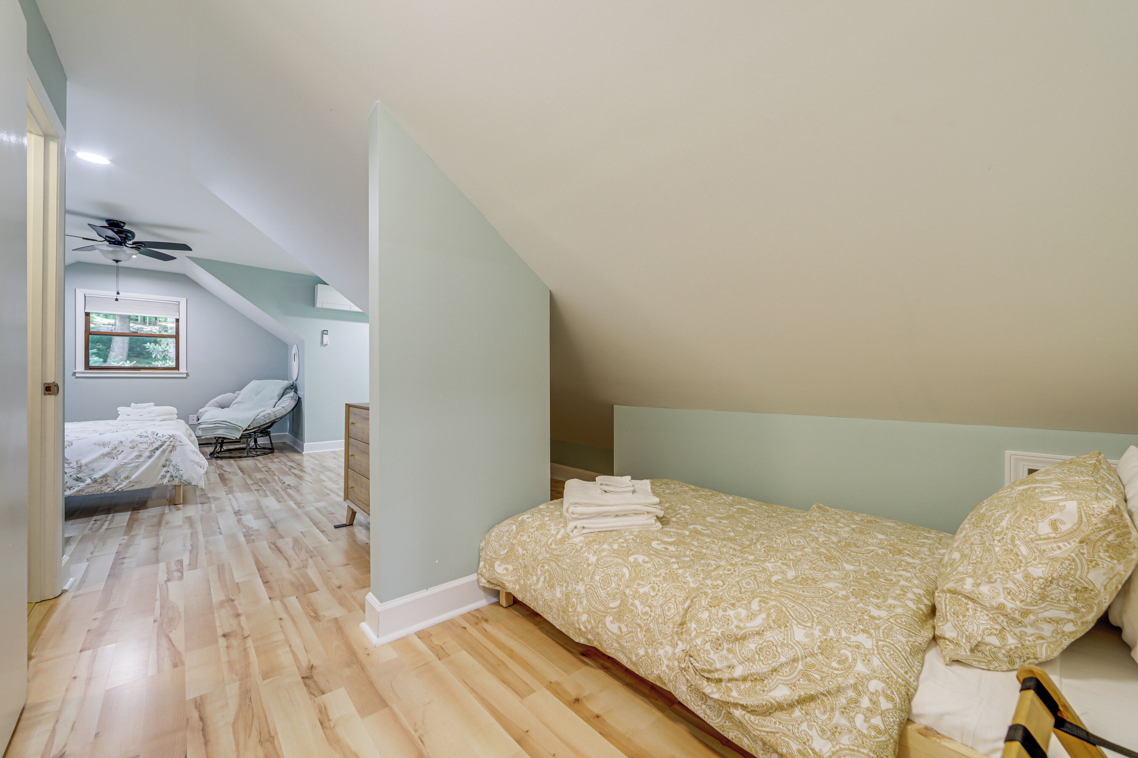 Un dormitorio con una cama, ventilador de techo y ventana.