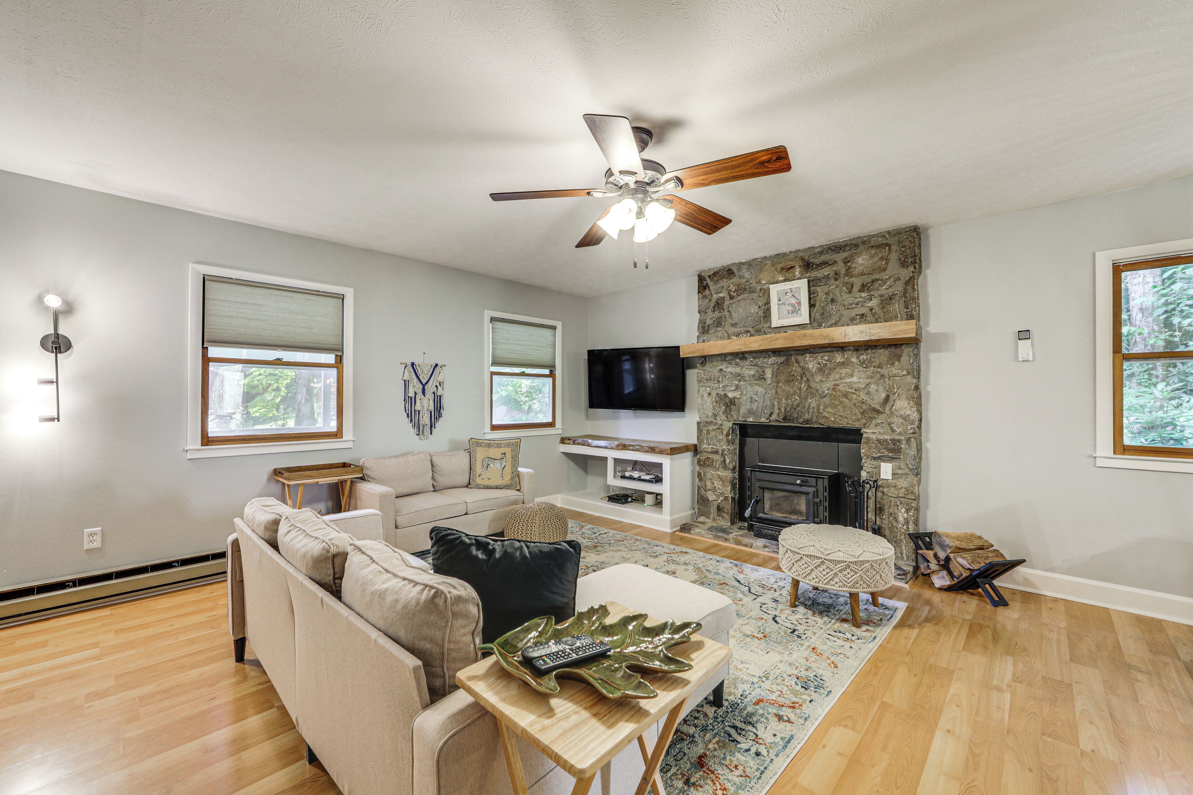 A living room with a beige sofa, a wooden coffee table, a television, a fireplace, and a stone accent wall.