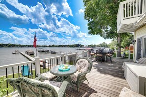 A deck with wicker furniture, a table with a glass, and an American flag. - Waterfront Clarklake Escape - Deck, Dock & Views (Clarklake)
