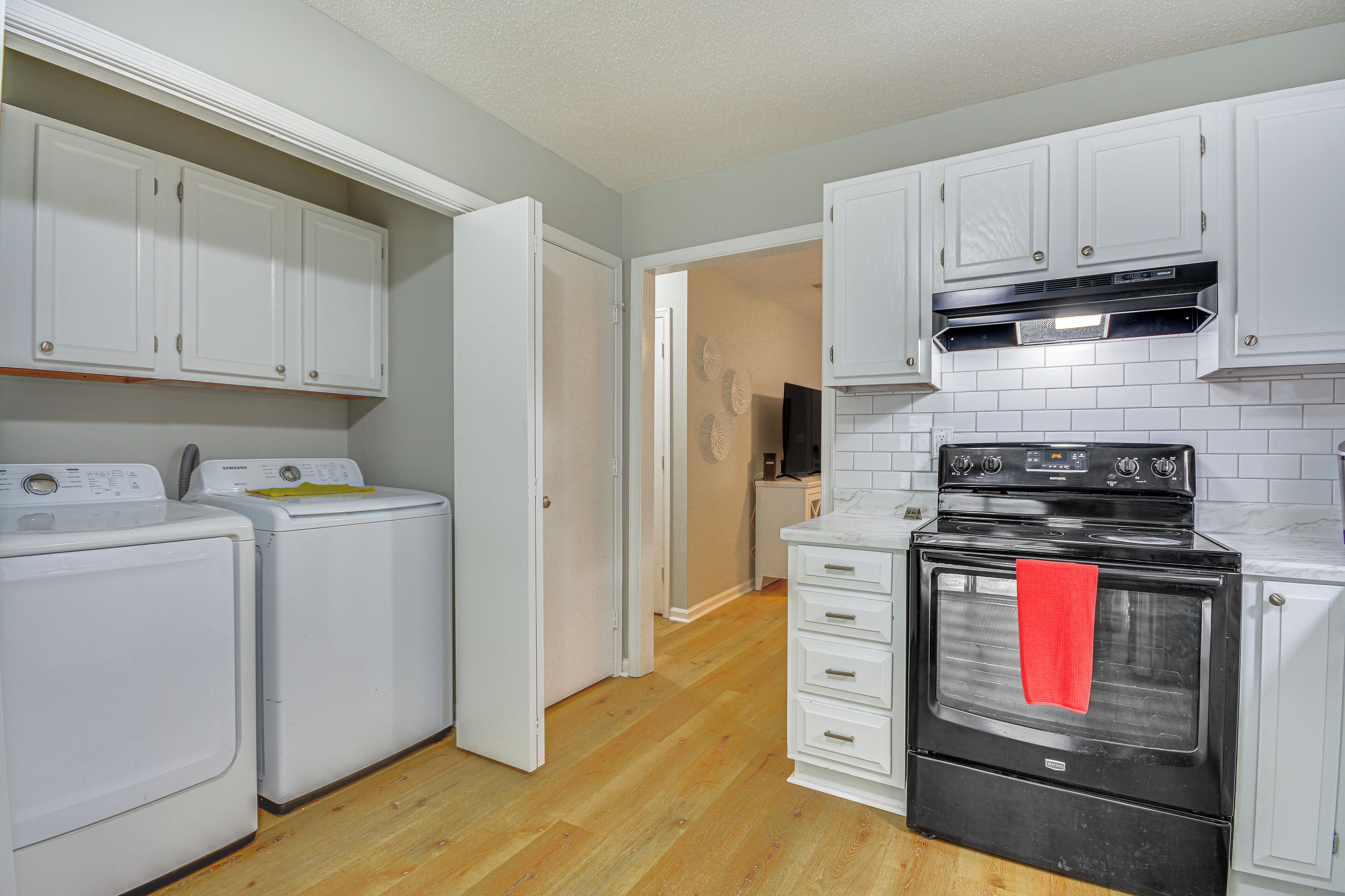A kitchen with white cabinets, a black oven, and a washing machine.