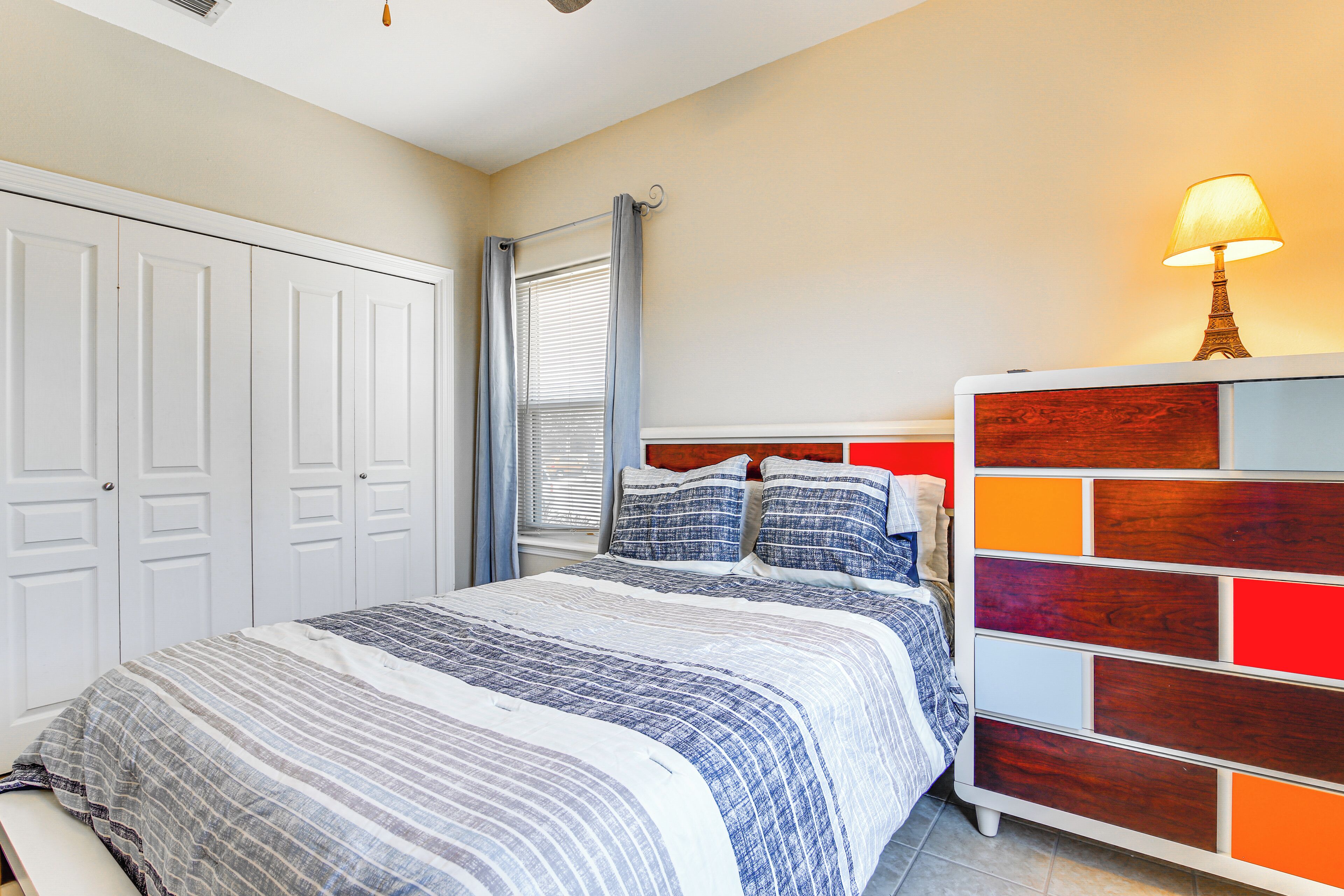 A bedroom with a bed, a nightstand, a lamp, and a window with curtains.