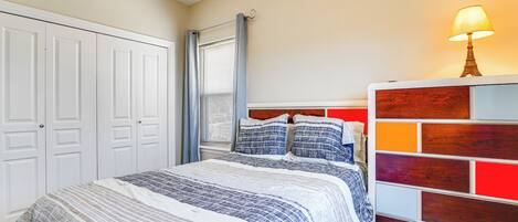 A bedroom with a bed, a nightstand, a lamp, and a window with curtains.