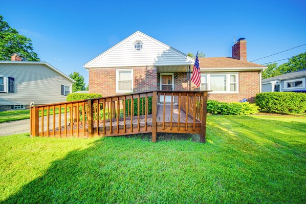 Uma casa de dois andares com um deck de madeira e uma bandeira americana.