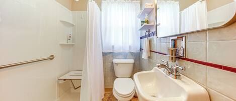 A bathroom with a toilet, sink, and shower area.