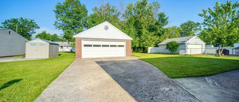 A residential garage with a concrete driveway, surrounded by a well-maintained lawn and trees.