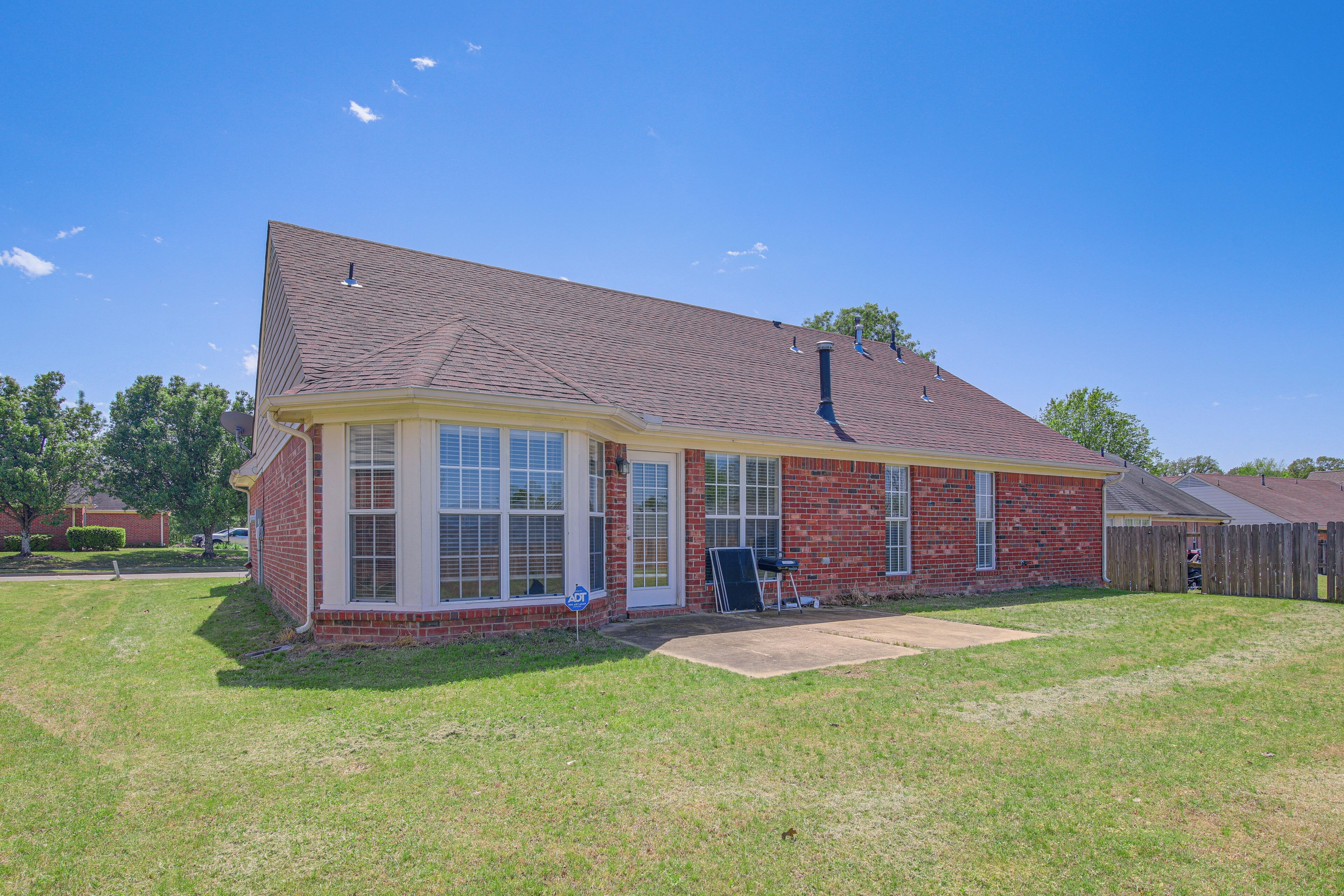 A single-story brick house with a gabled roof, a front porch, and a visible garage door.