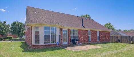 A single-story brick house with a gabled roof, a front porch, and a visible garage door.