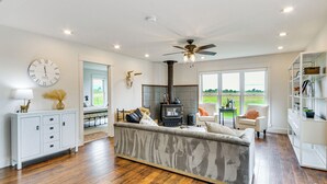 A spacious living room with a large sofa, a fireplace, and a view of the outdoors. - Lovely Roberts Home w/ Patio & Mountain Views! (Roberts)