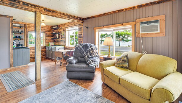 L’intérieur chaleureux d’un chalet avec un coin repas en bois, un fauteuil en cuir, un canapé jaune et une cuisine équipée d’un bar à café.
