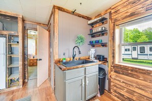 A compact kitchen with wooden cabinetry, a sink, and a window overlooking a green landscape. - Wisconsin Lakeside Cottage w/ Deck, Views (Stone Lake)