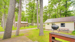 Un terrain de camping doté d’une terrasse en bois, de tables de pique-nique et d’un espace barbecue.
