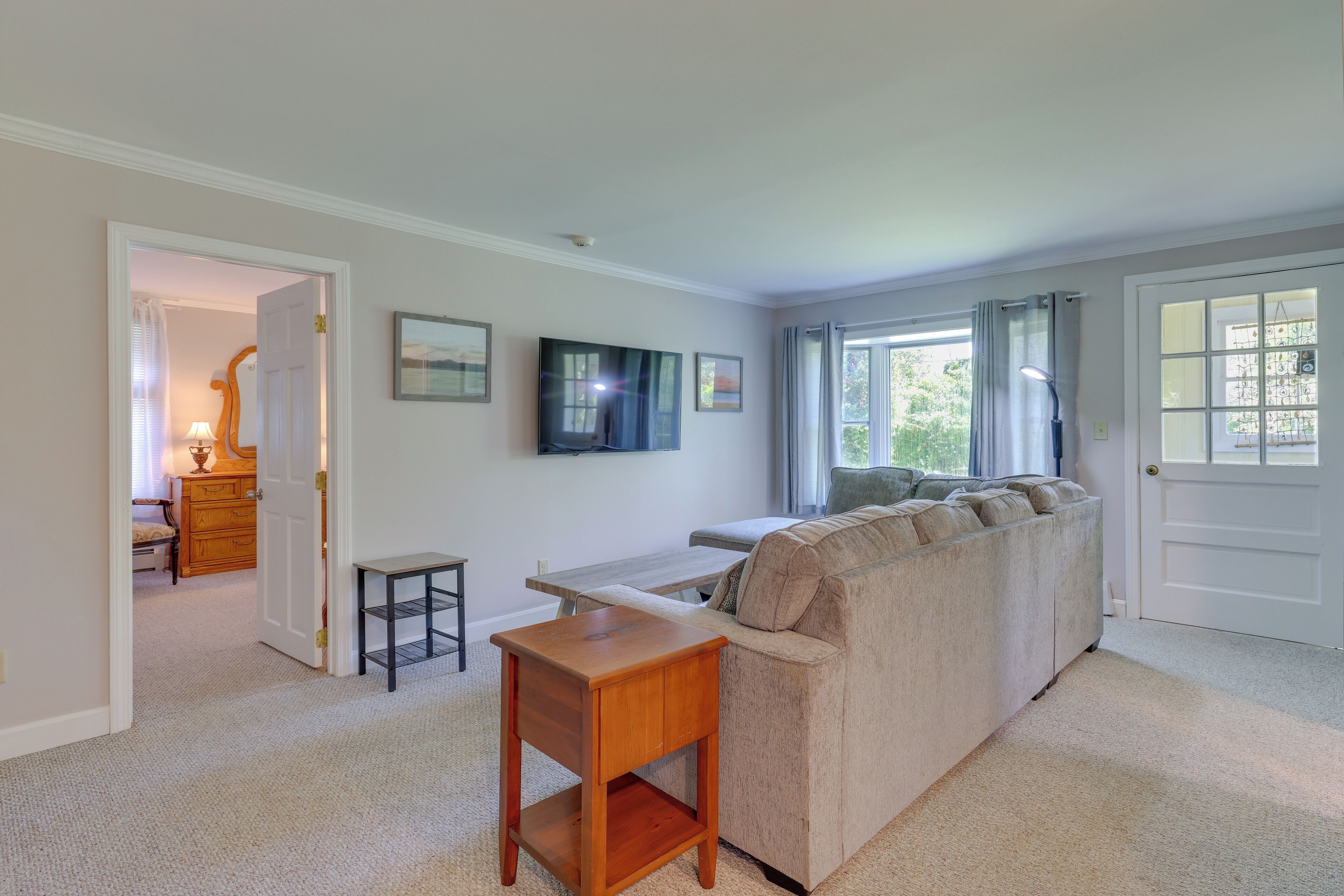 A living room with a sofa, a coffee table, and a TV mounted on the wall.