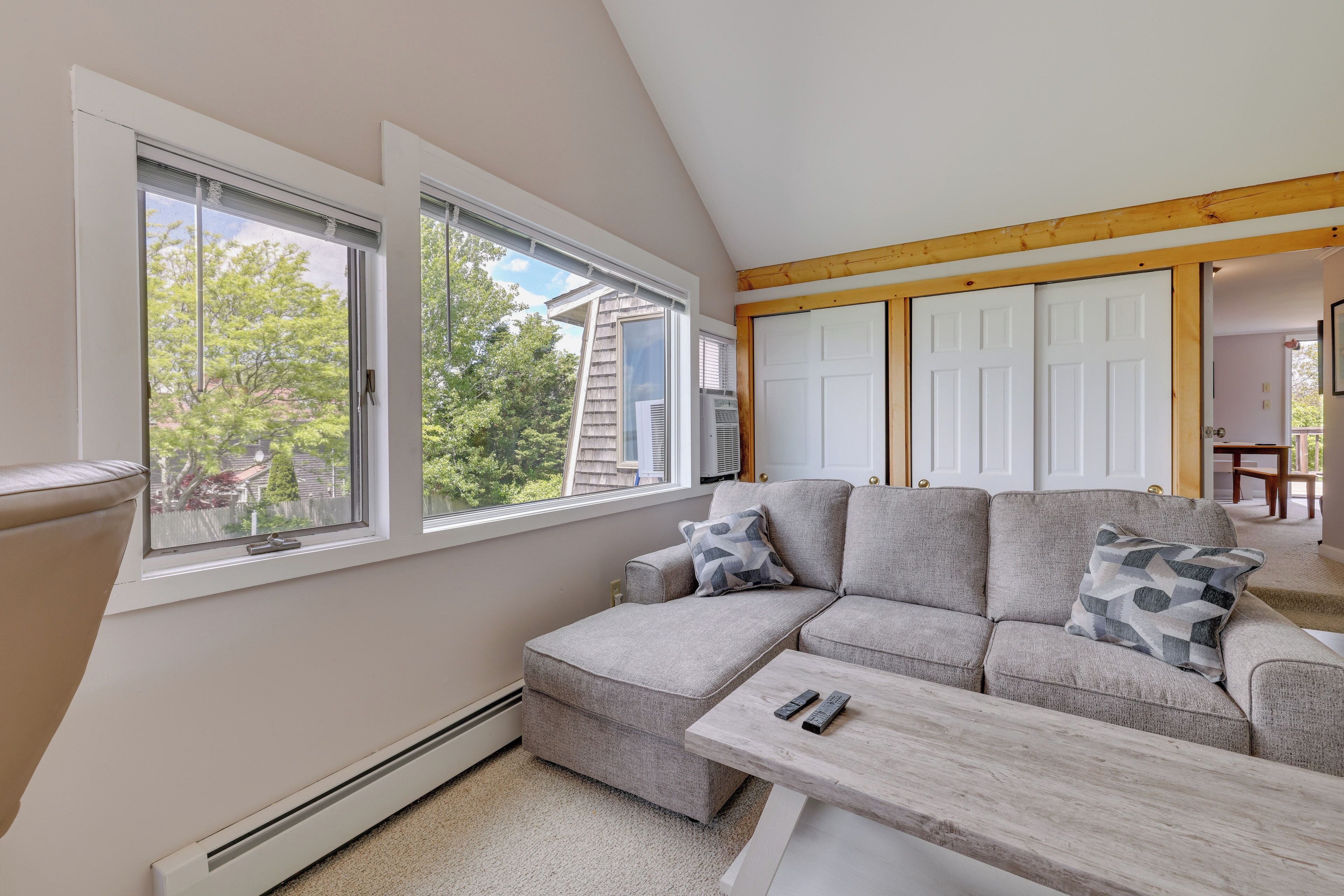 Una sala de estar moderna con un sofá modular, una mesa de centro de madera y ventanas amplias con vistas al exterior.