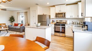 A modern kitchen with white cabinets, stainless steel appliances, and a dining area with a wooden table and chairs. - Lovely San Antonio Vacation Rental w/ Private Yard (San Antonio)