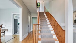 Un escalier avec des rampes en bois et des marches recouvertes de moquette, menant à l’étage supérieur.