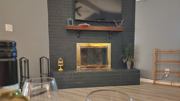 A modern living room with a fireplace, wooden shelves, and a potted plant.