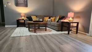 A living room with a grey sofa, a round wooden coffee table, and two side tables with lamps.