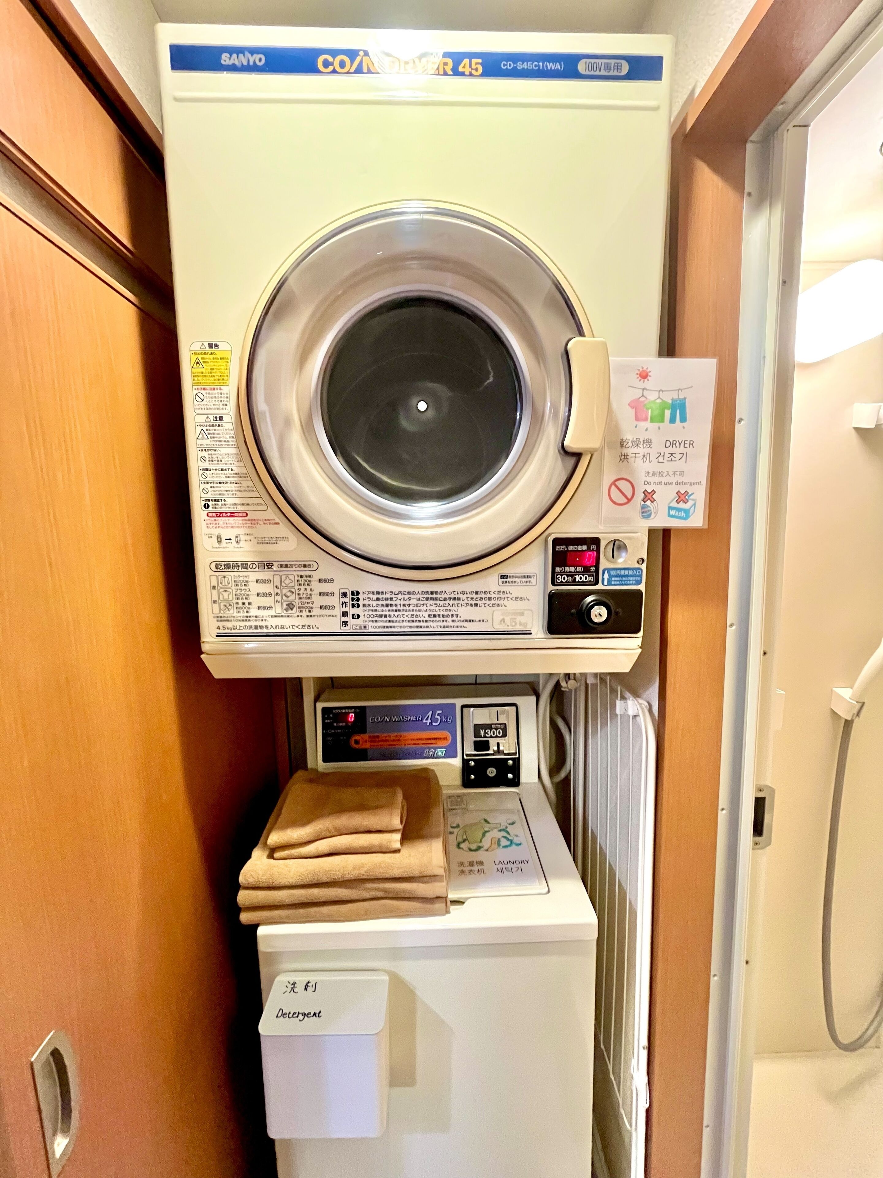 A compact, wall-mounted washing machine with a control panel and a small drying rack below it.