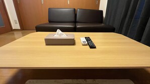 Una camera d'albergo con un tavolo di legno, un telecomando e un porta fazzoletti.